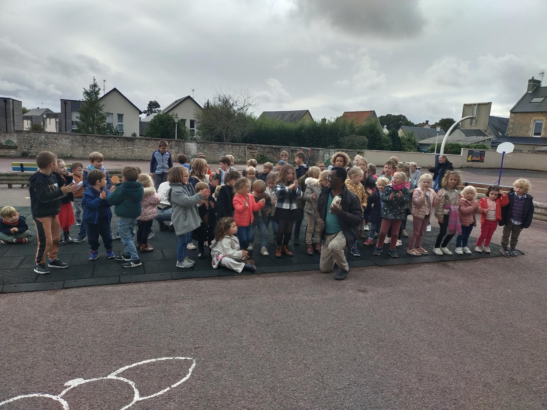 Temps d'échange et de chant avec le Père Florent dans la cour de l'école